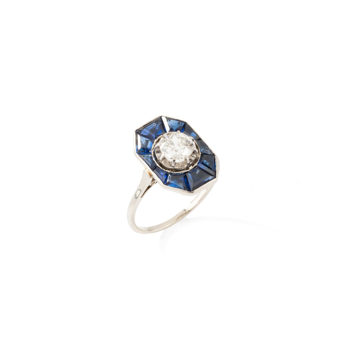 Bague Art Déco en or blanc centrée d'un diamants entouré de saphirs calibrés.