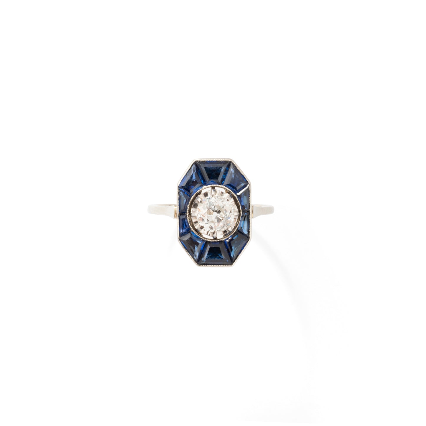 Bague Art Déco en or blanc centrée d'un diamants entouré de saphirs calibrés.