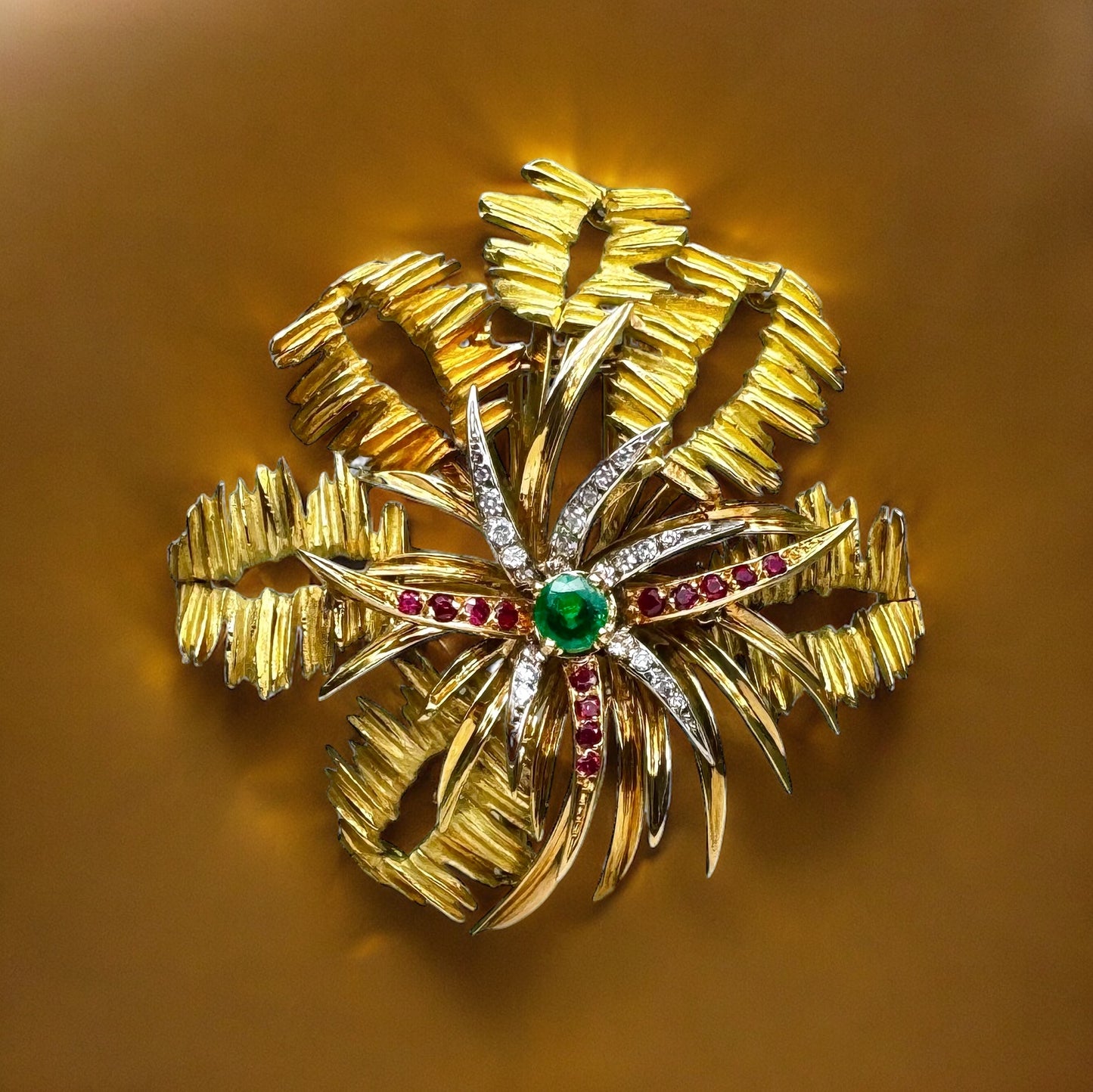 MELLERIO Broche en or jaune, le centre orné d’émeraude, de rubis et de diamants.