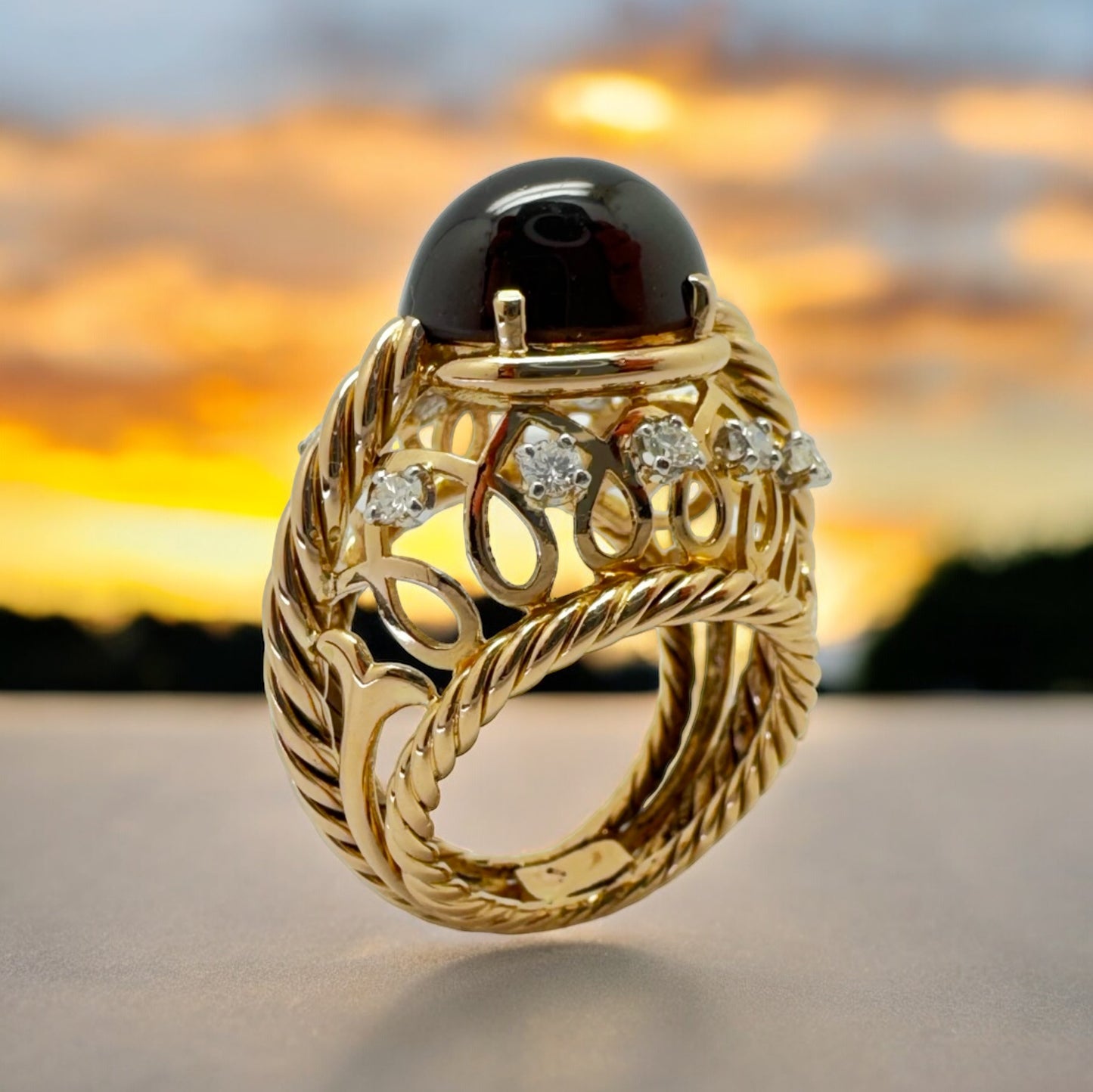 Bague dôme en or jaune ornée d’un grenat entouré de diamants.